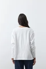 Remera de manga larga en color blanco, con calce relajado y diseño minimalista. Presenta un cuello redondo clásico y puños rectos, ideal para usar como prenda base en capas.