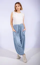 Pantalón ancho estilo babucha color azul claro, con cintura ajustable con cordón y grandes bolsillos laterales. El ruedo es ajustado al tobillo.