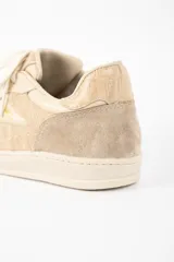 Zapatilla de cuero legítimo en tonos beige, con diseño combinado que incluye paneles de cuero liso, cuero con textura de reptil y detalles de gamuza en la puntera y el talón. Cuenta con cordones al tono y suela de goma.