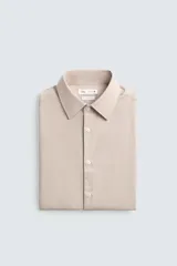 Camisa slim fit color beige, confeccionada en tejido de algodón, con cuello italiano y manga larga con puño de botón. Cierre frontal de botonadura.