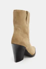 Botín de piel estilo cowboy en color beige, con detalle de pespuntes en el cuerpo, tiradores laterales y tacón alto en bloque.