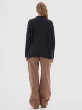 Buzo tejido de punto color beige, con cuello subido, diseño oversized y aberturas laterales en el ruedo.