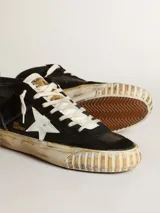 Zapatillas de media caña confeccionadas en cuero de color negro con efecto desgastado, inspiradas en la estética skate de los años ochenta. Presentan una estrella lateral en color blanco, refuerzo en el talón y suela de goma texturizada con acabado vintage.