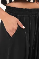 Pantalón negro de pierna súper amplia, confeccionado en denim fino y liviano con caída fluida. Tiene cintura elastizada con lazo regulable, bolsillos laterales y pinzas en la delantera.