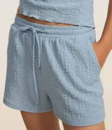 Bermuda de mujer confeccionada en tejido chambray texturizado, con corte recto, cintura elástica y lazo de ajuste.