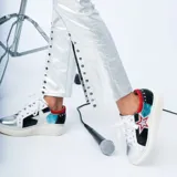 Championes de cuero metalizado plateado con detalles en negro, blanco, rojo y celeste, diseño con aplique de estrella lateral y suela de plataforma blanca.