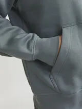 Canguro de manga larga color verde oscuro, con capucha ajustable mediante cordones, bolsillo tipo canguro y estampado en relieve con la frase "Originals Studio".