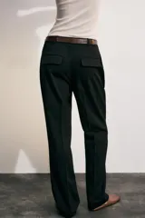 Pantalón de tiro alto color negro, de corte recto y pinzas frontales. Incluye un cinturón delgado de cuero marrón con hebilla metálica dorada.