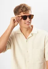 Lentes de sol redondos con montura gris translúcido y lentes verdes. Fabricados con acetato biodegradable y lentes de PMMA reciclado.