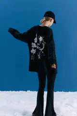 Buzo oversize de cuello alto confeccionado en frisa, con hombros caídos y bolsillos delanteros. Presenta una estampa artística en la espalda con motivos orientales, incluyendo un pez koi, flores y una mariposa.