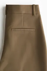 Pantalón cigarette color marrón, confeccionado en tejido elástico, con tiro estándar, bolsillos al bies y piernas ajustadas con raya marcada.