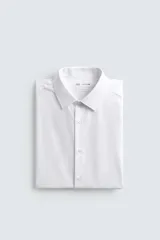 Camisa de corte slim fit confeccionada en tejido de algodón con textura. Presenta cuello italiano, manga larga con puños abotonados y cierre frontal mediante botonadura.