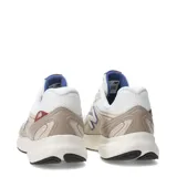 Championes urbanos New Balance modelo Amaste, con diseño en tonos beige y blanco, detalles en azul y rojo en el logo lateral y la lengüeta, confeccionados en malla y materiales sintéticos con suela de goma.