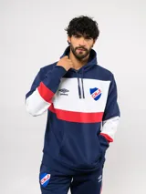 Canguro con capucha de Umbro del Club Nacional de Football, con diseño de bloques de color en azul, blanco y rojo. Presenta bolsillo frontal tipo canguro, cordones ajustables en la capucha y logos bordados del club y la marca.