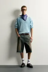 Bermuda de denim de algodón con efecto lavado desgastado en tonos marrones y azules. Tiene tiro medio, diseño de cinco bolsillos, pierna recta de corte holgado y bajo con acabado irregular. Cuenta con cierre frontal de cremallera y botón metálico.