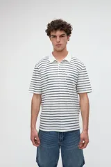 Remera polo de manga corta con diseño a rayas horizontales marrones sobre base blanca, cuello camisero en color blanco con media cartera de botones y aberturas laterales en el dobladillo.