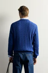 Sweater de punto verde con diseño de trenzas, cuello redondo y manga larga, de corte regular fit y acabados en rib.
