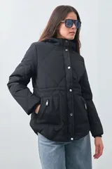 Campera matelasé color negro con capucha, cierre frontal con botones a presión y bolsillos frontales con cierre.