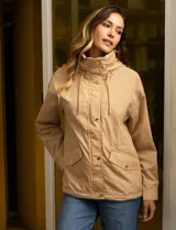 Campera color beige de poliéster, marca Michael Kors. Tiene cierre central oculto con botones a presión, bolsillos delanteros, capucha escondida en el cuello y avíos metálicos dorados con logo.