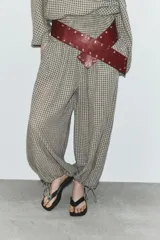 Pantalón de tiro medio con estampado de cuadros vichy en tonos beige y marrón. Cuenta con cintura elástica tipo nido de abeja y bajo ajustable con cordones.