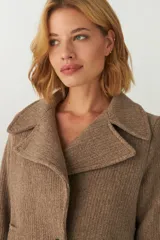 Chaquetón color beige con cuello, abrochadura simple con botón en el cuello, bolsillos ojal y detalle de martingala en mangas. Prenda con forro al tono.