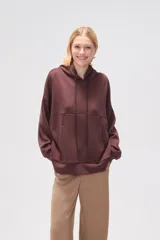 Canguro negro holgado con capucha y cordones ajustables, mangas largas y bolsillos laterales.