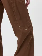 Pantalón de tiro medio y pierna ancha confeccionado en denim de algodón grueso. Presenta un diseño a rayas verticales en tonos azul y celeste, con costuras en contraste color rojo, bolsillos laterales tipo cargo y remaches metálicos.