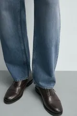 Zapato de vestir tipo oxford con puntera reforzada, confeccionado en piel de color marrón oscuro. Presenta cierre mediante cordones al tono, forro interior y plantilla de piel, y suela a contraste con tacón bajo.