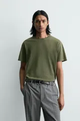Camiseta de corte relajado, color verde oliva con efecto lavado. Presenta cuello redondo, manga corta y un gráfico estampado en la espalda.