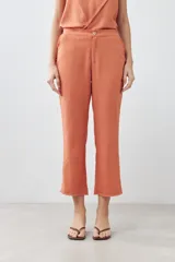 Pantalón capri color durazno de lino con efecto desflecado en el ruedo.