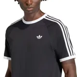 Remera Adidas negra con cuello redondo y ribetes blancos en el cuello y las mangas. Presenta las tres rayas características de la marca en los hombros y el logo del trébol bordado en el pecho.