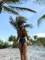 Traje de baño enterizo color verde militar brillante, con escote asimétrico de un solo hombro y recortes laterales con aros de madera.