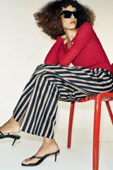 Pantalón de tiro alto y pernera recta con estampado de rayas verticales en tonos azul, marrón y beige. Incluye un cinturón delgado de color marrón oscuro con hebilla metálica dorada.