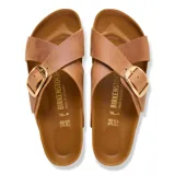Sandalias Birkenstock modelo Siena Big Buckle, color cognac. Presentan un diseño de correas cruzadas en cuero con una hebilla grande metálica dorada ajustable. Poseen la clásica plantilla anatómica de corcho y látex con suela de goma antideslizante.