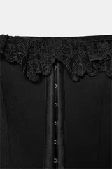 Top corsetero blanco con escote cuadrado y tirantes anchos con volados de encaje. Presenta costuras marcadas y cierre frontal con ganchos metálicos.