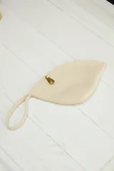 Sobre de mano con forma de hoja, tejido en soga de algodón color beige claro. Posee una correa de mano tejida y un pequeño dije metálico dorado en forma de pez o ballena.