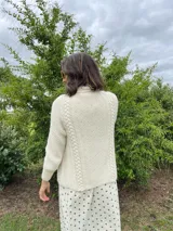 Cardigan tejido a mano color crudo, con solapa en el escote y punto delicado.