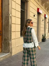 Chaleco de corte sastrero con estampado de cuadros en tonos verde, beige y negro, con cierre frontal de botones.