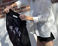 Chaqueta corta azul marino de terciopelo con cuello mao, botones dorados y bordado floral en el frente.