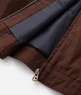 Campera masculina modelo trucker confeccionada en sarga de algodón. Presenta cuello de terciopelo en contraste, cierre frontal con cremallera, manga larga y bolsillo con cremallera en el pecho.