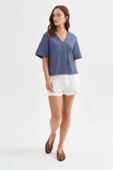 Blusa de viscosa color beige con cuello en V, mangas cortas amplias y detalles de pespuntes decorativos en el frente y las mangas.