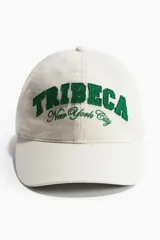 Gorra de sarga color blanco off-white con efecto lavado, visera curva y bordado frontal en color verde con el texto "TRIBECA New York City".