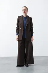 Camisa negra de estilo sastrero con cuello clásico, frente abotonado y mangas largas con puños ajustados. Presenta un diseño con hombreras sutiles que aportan estructura a la prenda.