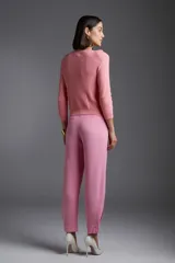 Sweater de punto color rosa con cuello redondo y apliques de flores en el escote.