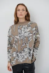 Buzo de tejido de punto con diseño floral en contraste, cuello redondo y mangas largas. Presenta una textura suave y un corte holgado.