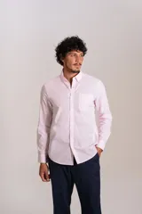 Camisa de manga larga confeccionada en tejido poplin con diseño de rayas verticales finas en color rosado y blanco. Presenta cuello abotonado (button-down), cierre frontal con botones y un bolsillo en el pecho.