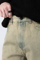 Jean de corte mom oversize, color negro lavado, con diseño de cinco bolsillos y cierre frontal con botón y cremallera.