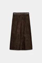 Falda midi de tejido efecto ante en color marrón oscuro, con tiro medio, trabillas en la cintura y cinturón ajustable con hebilla metálica. Presenta un diseño de bajo recto con una abertura frontal central y cierre lateral con cremallera oculta.