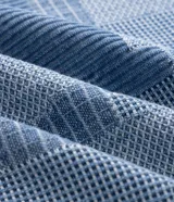 Camisa de jean de algodón con textura jacquard y diseño geométrico, de corte boxy, cuello con solapa, manga corta y cierre frontal con cremallera.