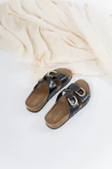 Sandalias de cuero negro con tiras cruzadas y hebillas metálicas doradas. Base anatómica de corcho y goma antideslizante.